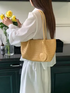 Cream yellow woven leather shoulder tote bag with heart charm, stylish casual daily purse.