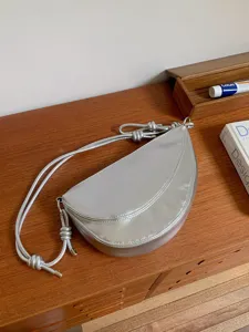 Silver crescent shoulder bag for women, stylish saddle bag with knotted strap design.