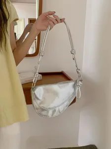Close-up view of a chic silver metallic hobo shoulder bag with unique knotted strap detail.