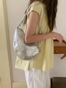 Silver metallic underarm shoulder bag, trendy crescent design with knotted strap details.