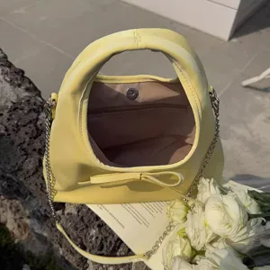 Detailed view of the yellow hobo shoulder bag featuring a cute bow strap and chic chain handle.