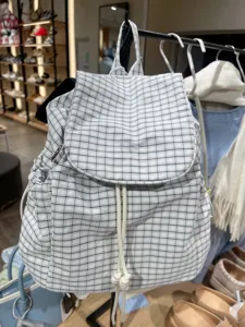 Detailed close-up view of casual plaid backpack featuring drawstring and flap design.