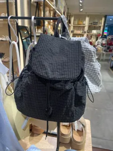 Detailed view of casual black and white grid backpack with drawstring and flap closure.