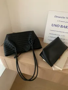 Black woven leather tote bag with matching pouch and heart charm for daily casual use.