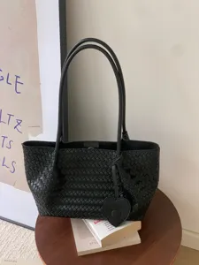 Black woven leather tote bag with double handles and heart pendant for casual daily use.