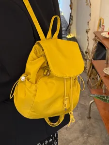 Yellow nylon drawstring backpack detail, casual daily school daypack, stylish travel bag.