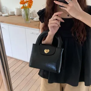 Detail shot of a black glossy handbag with a gold heart lock, lifestyle mirror setting.