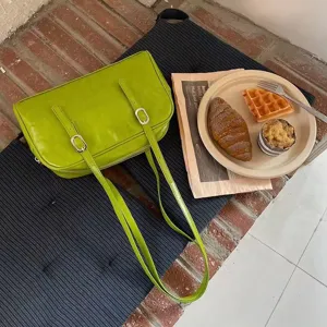 Green leather shoulder bag detail shot featuring chic double belt buckle design and lifestyle vibe.
