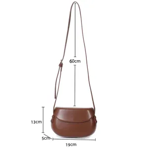Brown leather saddle bag for women, stylish crossbody shoulder bag with adjustable strap.