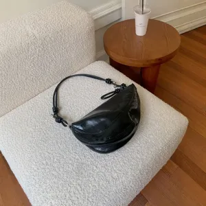 Black glossy crescent saddle bag for women, stylish minimalist underarm shoulder handbag.