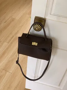 Vue détaillée d'un sac à bandoulière rétro en cuir PU marron foncé suspendu à une poignée.