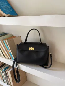 Gros plan détaillé du sac à main en cuir PU noir doté d'une fermeture tournante dorée.