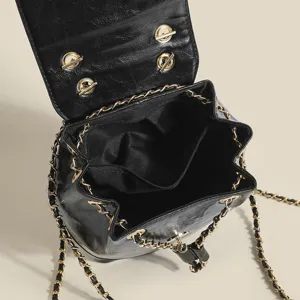 Detailed view of black leather chain backpack, stylish flap design with gold hardware.