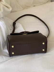 Détail de sac à bandoulière en cuir PU marron foncé, style vintage avec détails dorés.