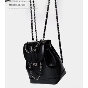 Black synthetic leather backpack with metal chain straps and chic flap closure for women.