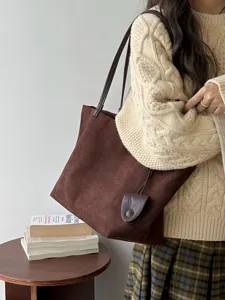 Detail view of the brown suede tote bag with shoulder straps and small pouch in autumn.