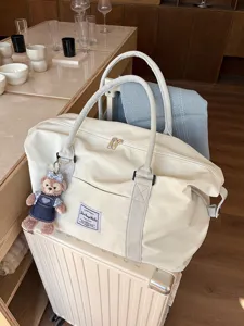 Large capacity beige travel duffel bag with a luggage sleeve and cute bear charm.