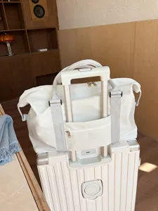 Detailed view of off-white travel duffel bag with luggage sleeve and sturdy handles.
