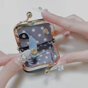 Detail view of mini clasp coin purse interior with polka dot lining and snap button.