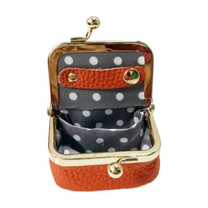 Detail view of mini kiss-lock coin purse, orange textured leather and gold frame interior.