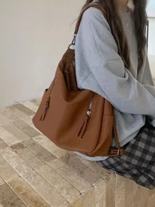 Detailed shot of a stylish brown leather hobo shoulder bag worn by model, large capacity.