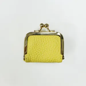 Detailed close-up view of mini yellow textured leather kiss-lock coin purse with gold metal frame.