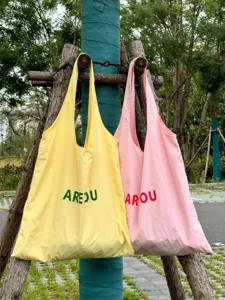 Detailansicht von leichten Stofftaschen in sanftem Gelb und Rosa im Freien präsentiert.