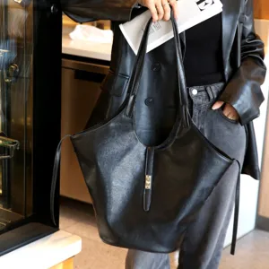 Black leather tote bag detail, featuring a central metal lock and spacious commuter design.