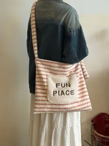 Plush striped shoulder tote bag with embroidered front pocket for casual everyday use.