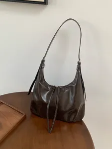 Vista dettagliata della borsa a tracolla hobo in pelle marrone scuro retrò su tavolo in legno.
