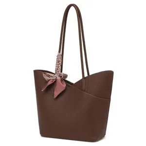 Vue détaillée du sac cabas en cuir marron avec une élégante écharpe en soie décorative.