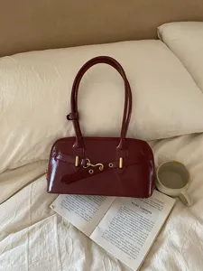 Detailed view of a retro dark red patent leather bowling shoulder bag with chic metal buckle accent.