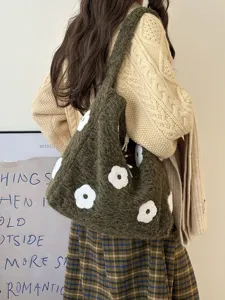 Close-up detail of dark green fuzzy shoulder bag with white flower embroidery, forest style.