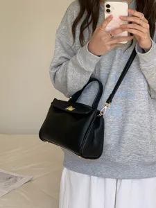 Vue détaillée du sac bandoulière en cuir PU noir avec poignée, porté dans un décor quotidien.