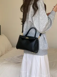 Vue détaillée d'un élégant sac à main en cuir PU noir avec quincaillerie dorée dans un décor cosy.