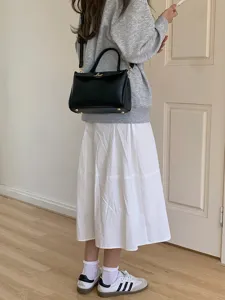 Sac bandoulière minimaliste en cuir PU noir présenté dans une tenue décontractée quotidienne.