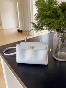 Détail rapproché du sac à main en cuir PU blanc avec fermoir tournant doré et poignée.
