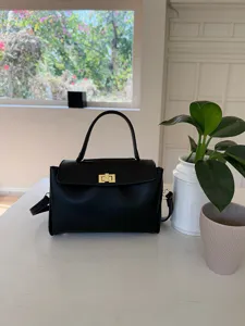 Gros plan détaillé de l'élégant sac à main en cuir PU noir avec quincaillerie dorée.