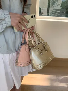 Stylish patent leather shell handbag for women with chic metal studs and chain accessory.