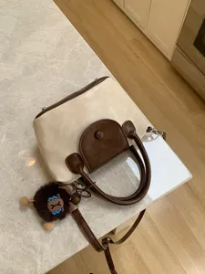 Chic two-tone top handle crossbody bag with cute plush pendant for women stylish daily wear.