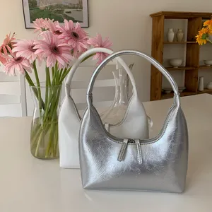 Detail shot of silver and white crinkled hobo bags on a white tabletop, cozy interior.
