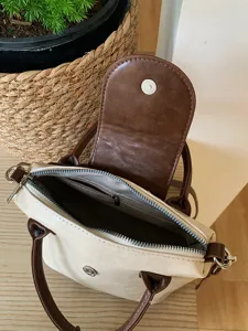 Detail view of women's contrast color handbag interior, zipper pocket, and magnetic snap.