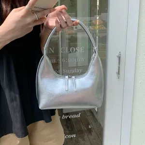 Silver metallic hobo bag detail shot showing glossy leather texture and chic crescent shape.