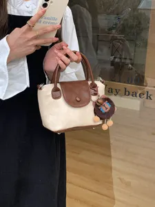 Chic two-tone handbag with brown flap, top handles, and cute plush charm for daily stylish wear.
