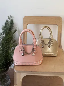 Close-up detail of stylish pink and gold dome handbags with chain and dice charms on a chair.