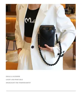 Schwarze herzförmige Handytasche Detailansicht mit elegantem Perlenarmband und Design.