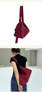 Détail de sac porté épaule en cuir souple bordeaux, sac hobo minimaliste avec lanière.