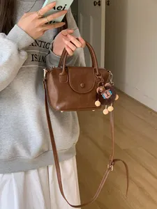 Chic brown PU leather mini handbag detail, featuring top handle and cute fluffy charm.