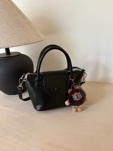 Stylish black leather crossbody handbag for women with top handle and cute plush charm detail.