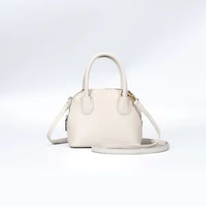 Detailed view of the stylish beige dome handbag with smooth leather texture and gold hardware.